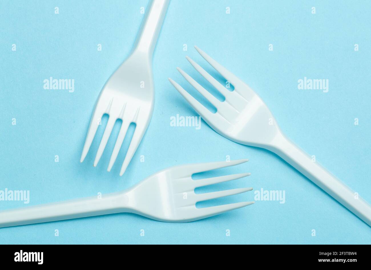 Fourchettes en plastique sur fond bleu. Déchets plastiques et pollution concept. Banque D'Images