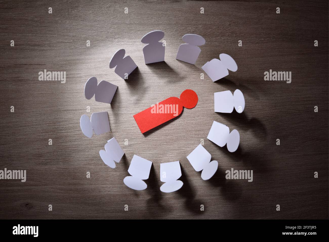 Concept de victime de violence sociale par la discrimination et le harcèlement avec des coupures de papier de petits hommes autour d'un autre couché sur le sol. Banque D'Images