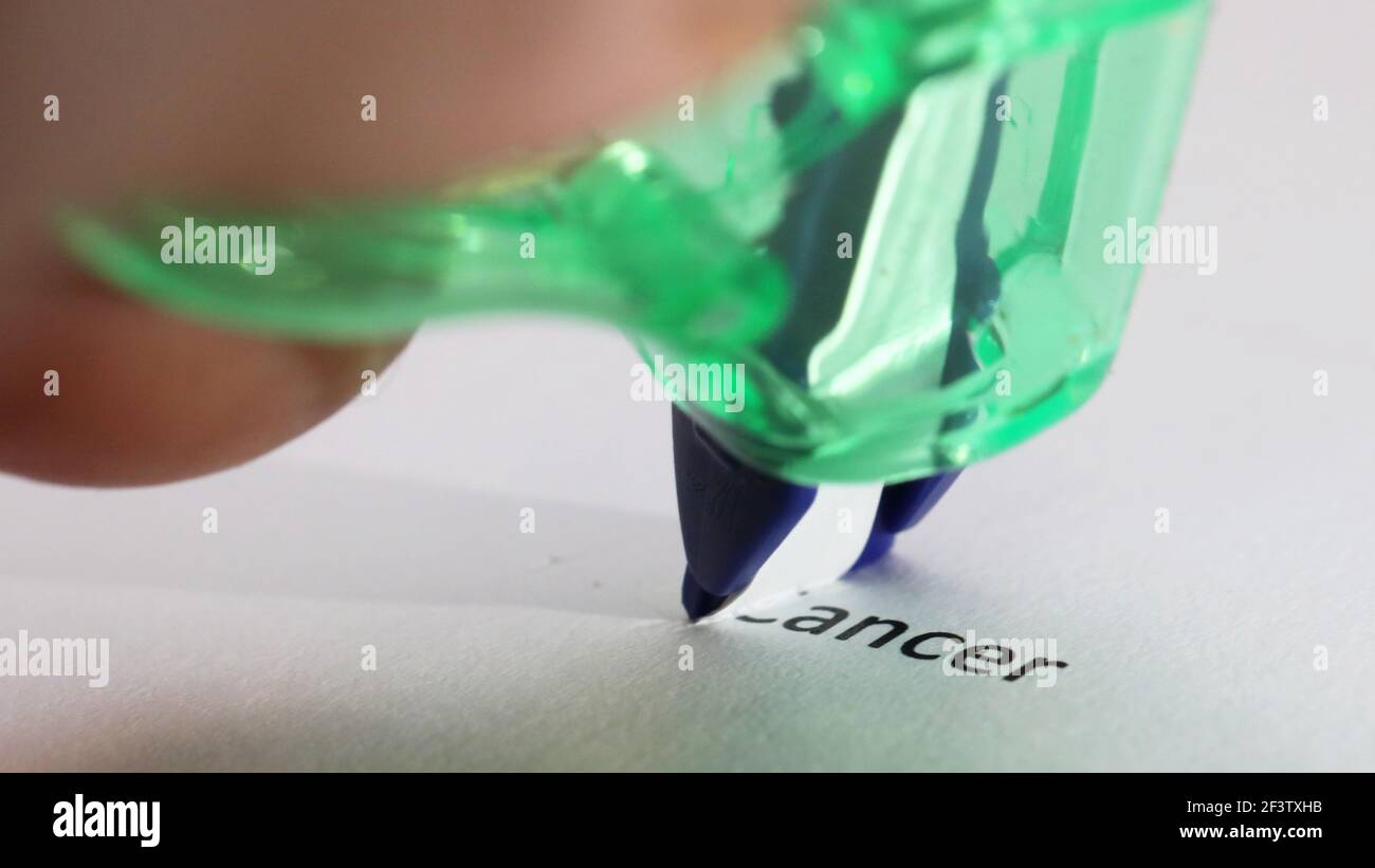 Éliminer le concept de cancer. Le mot cancer sur le point d'être enlevé, couvert ou effacé symboliquement par la bande de correction. Gros plan sur le texte. Traitement Banque D'Images