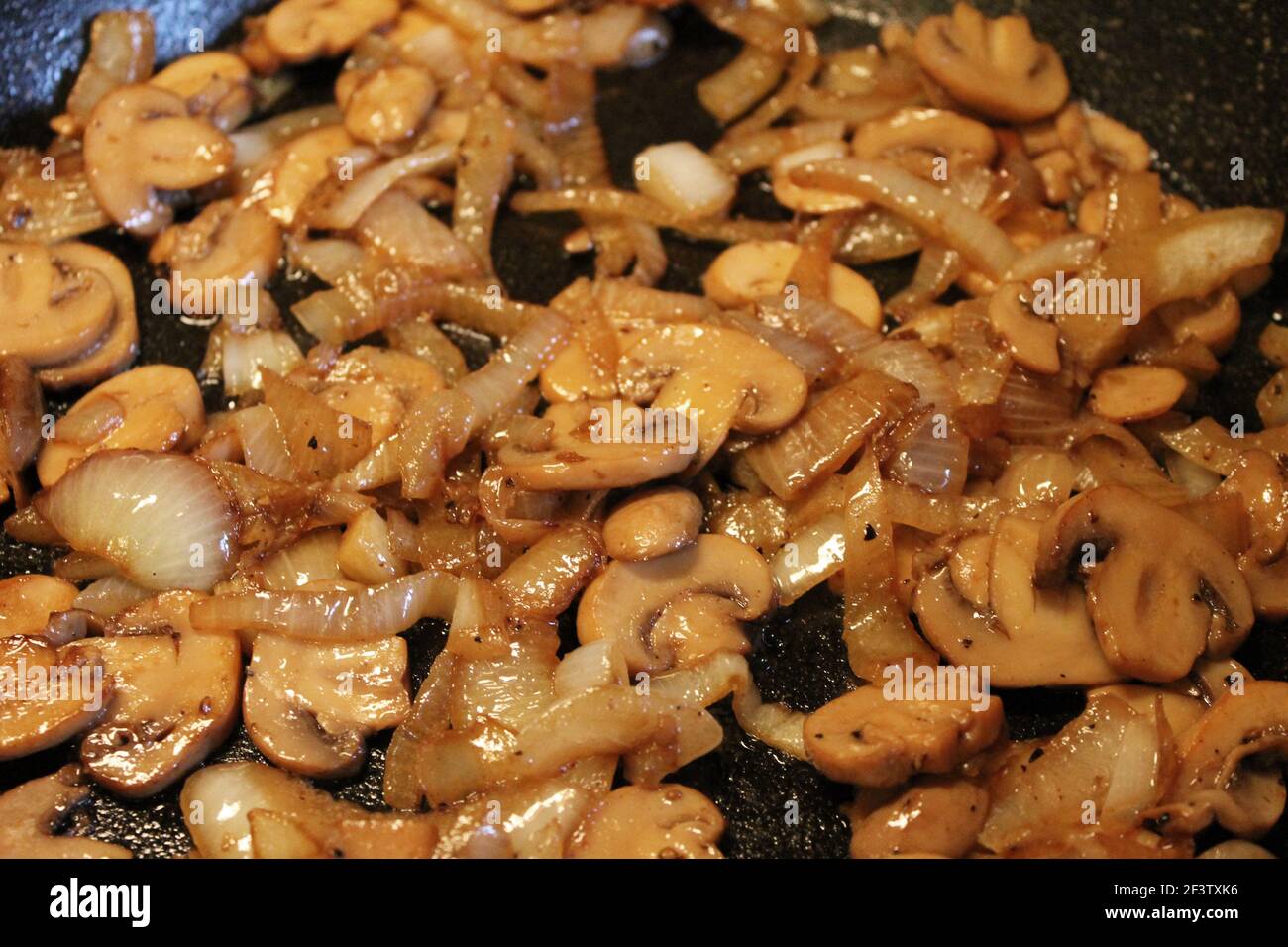 Gros plan de champignons sautés et d'oignons dans une poêle en fonte. Banque D'Images