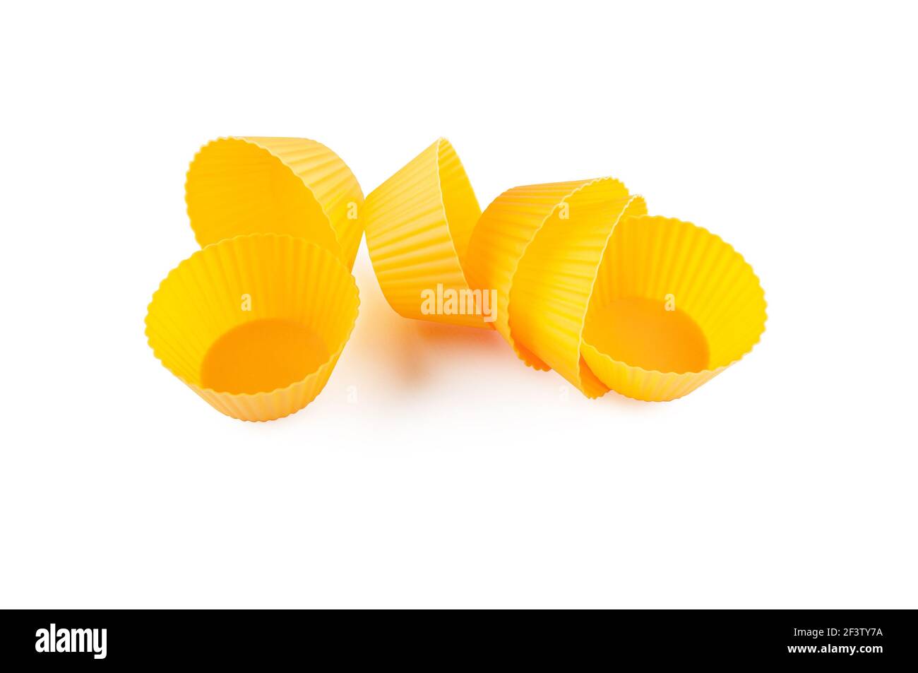 Moules en silicone jaune orange pour la cuisson de muffins et de cupcake isolés sur blanc. Banque D'Images