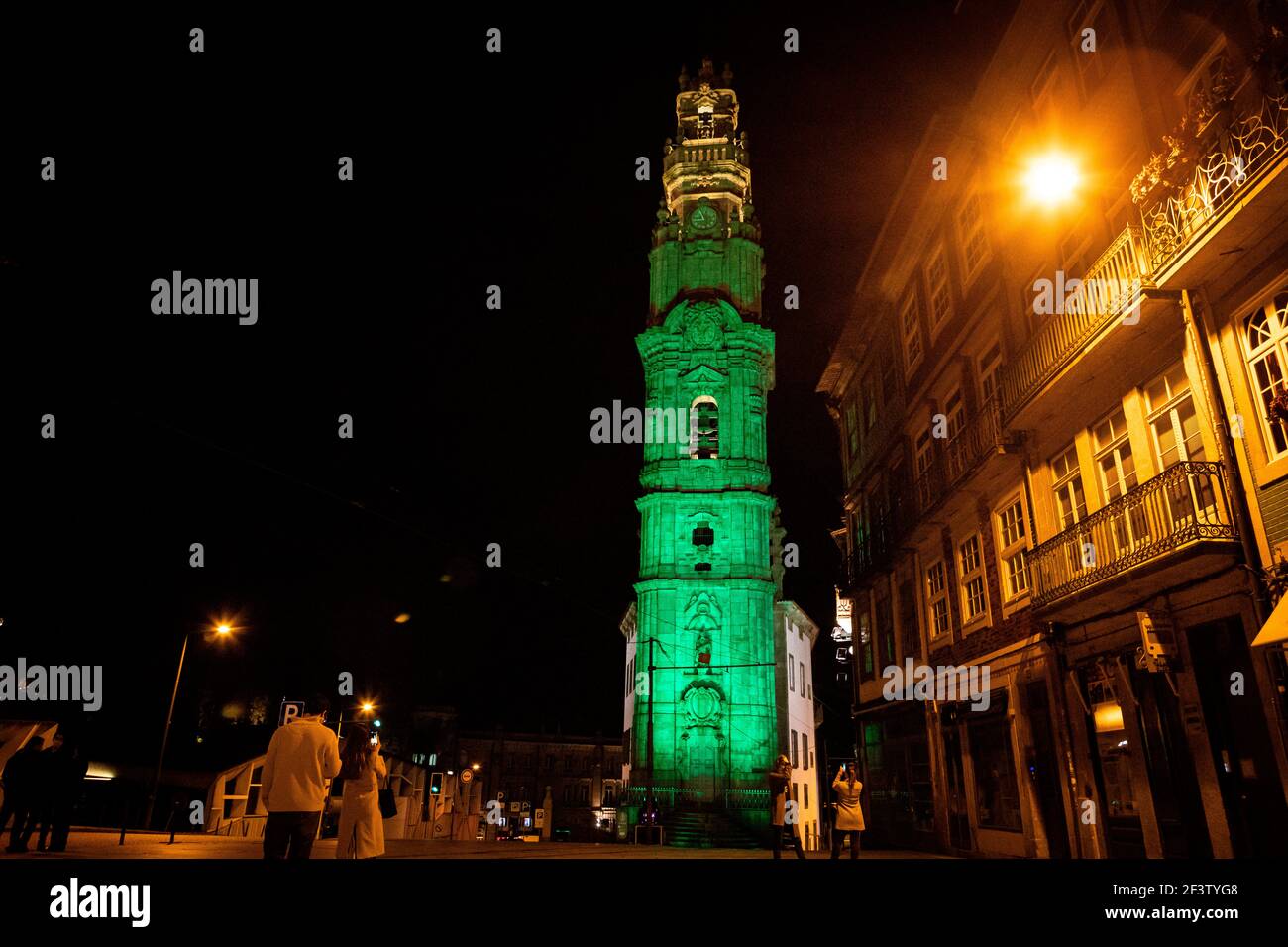 Porto, Portugal. 17 mars 2021. Les gens prennent des photos de la Tour Clérigos illuminée en vert.le Greening global est tenu par Tourism Ireland et vise à apporter une certaine positivité et l'espoir en prenant un feu vert dans autant de lieux autour du monde que possible, Donner à la diaspora irlandaise un sentiment de connexion avec la maison tout en célébrant la St Patrick's Day. La tour Clérigos rejoint la fête de la Saint-Patrick, illuminée de lumière verte de 19:00 à minuit. (Photo par Teresa Nunes/SOPA Images/Sipa USA) crédit: SIPA USA/Alay Live News Banque D'Images