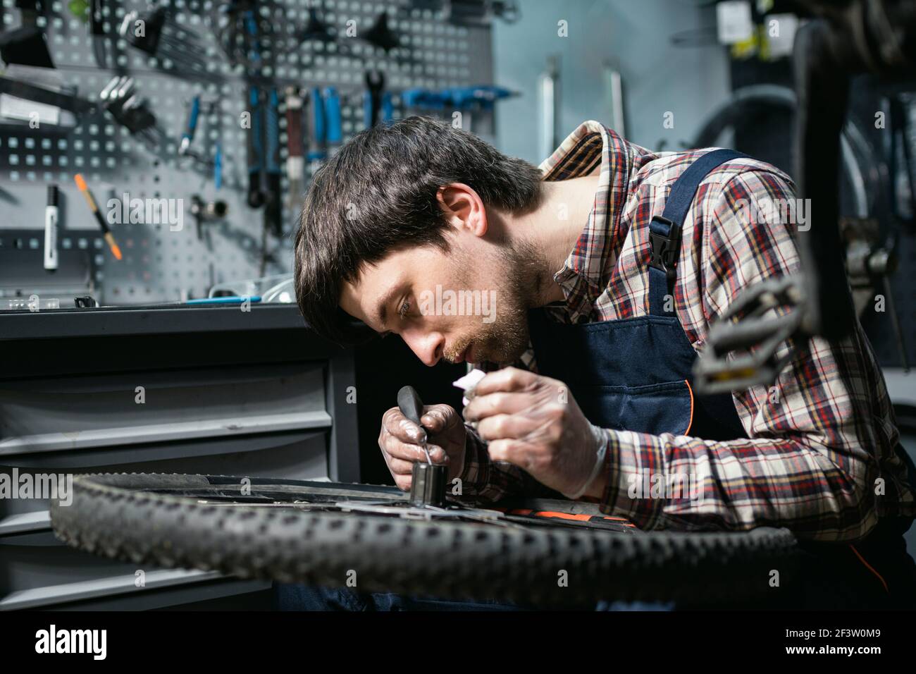 Atelier de vélo mécanique fixant la roue de vélo dans l'atelier. Réparation par un technicien de maintenance, cycle d'entretien. Velocipede réparation de vélo dans la boutique de vélos. Réparation de vélos Banque D'Images
