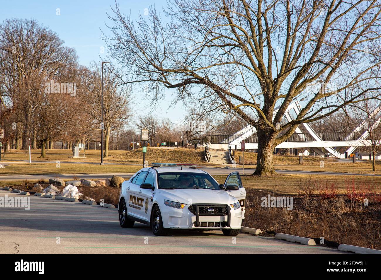 Un policier arrête sa voiture de patrouille blanche le long d'un terrain de stationnement sur le campus de l'Université Purdue fort Wayne à ft. Wayne, Indiana, États-Unis. Banque D'Images