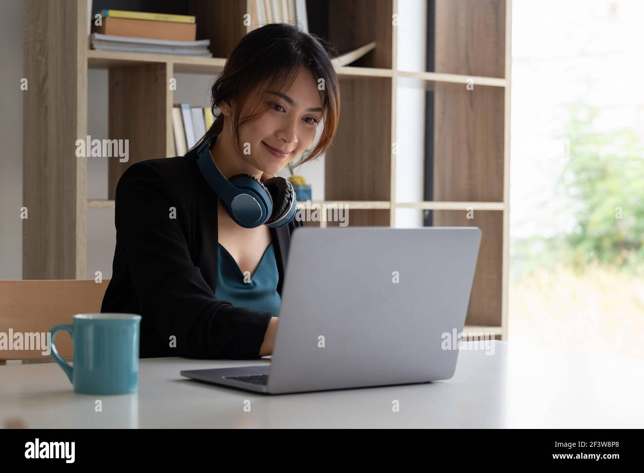 Portrait d'une femme asiatique étudiant en ligne avec un ordinateur portable pendant asseyez-vous à la table et à l'ordinateur portable à la maison Banque D'Images
