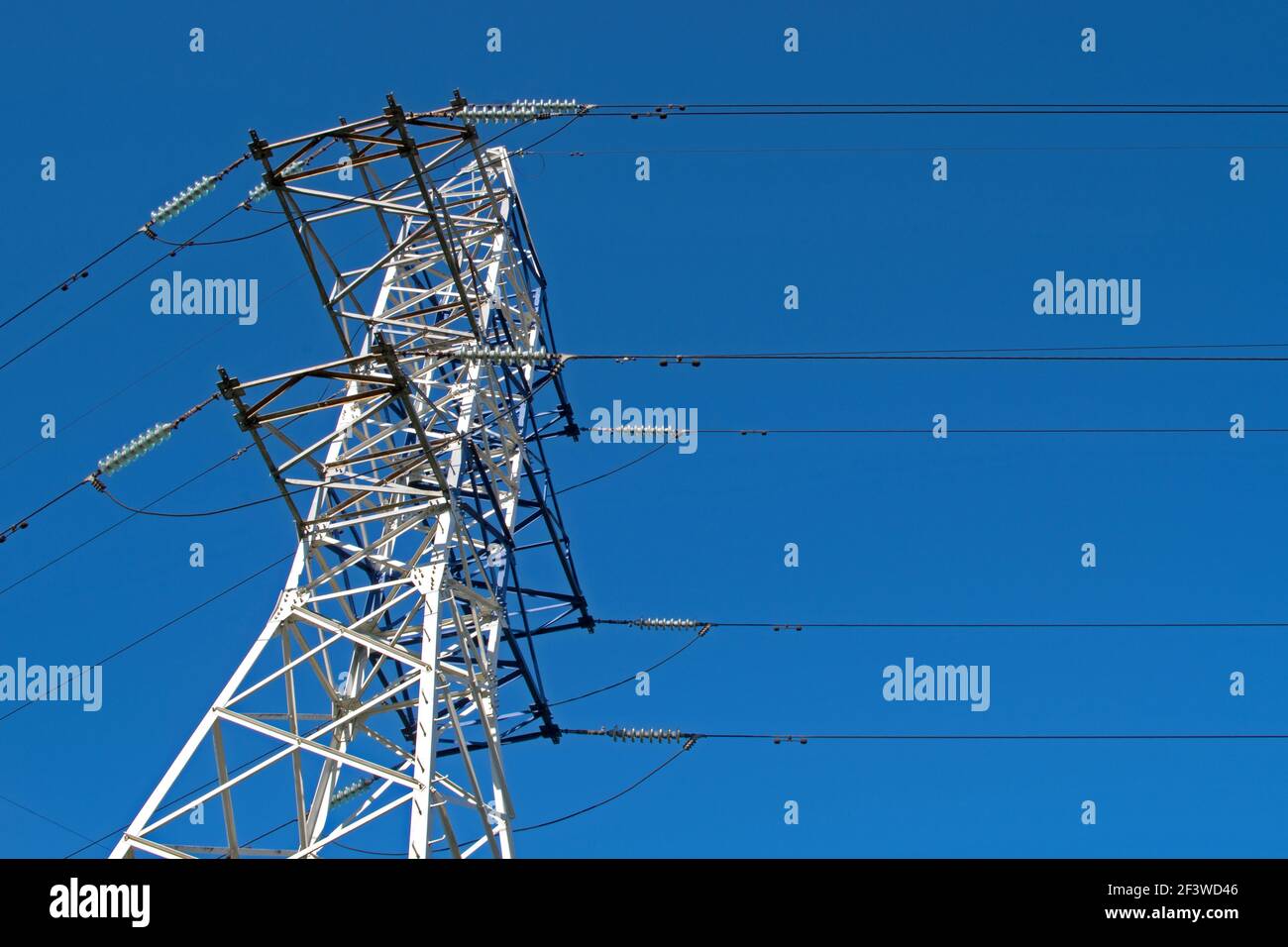 Une structure de cadre en métal blanc qui s'effile vers le haut est une puissance tour de transmission avec supports et groupes d'isolants en céramique reliant haute tension c Banque D'Images