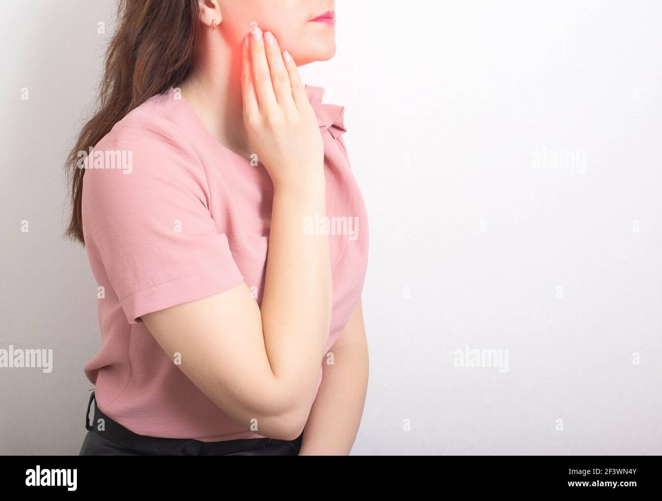 Une fille brune tient avec sa main la mâchoire d'une dent de sagesse malade avec un kyste. Concept de maladie dentaire en dentisterie, inflammation des gencives, copier l'espace pour Banque D'Images