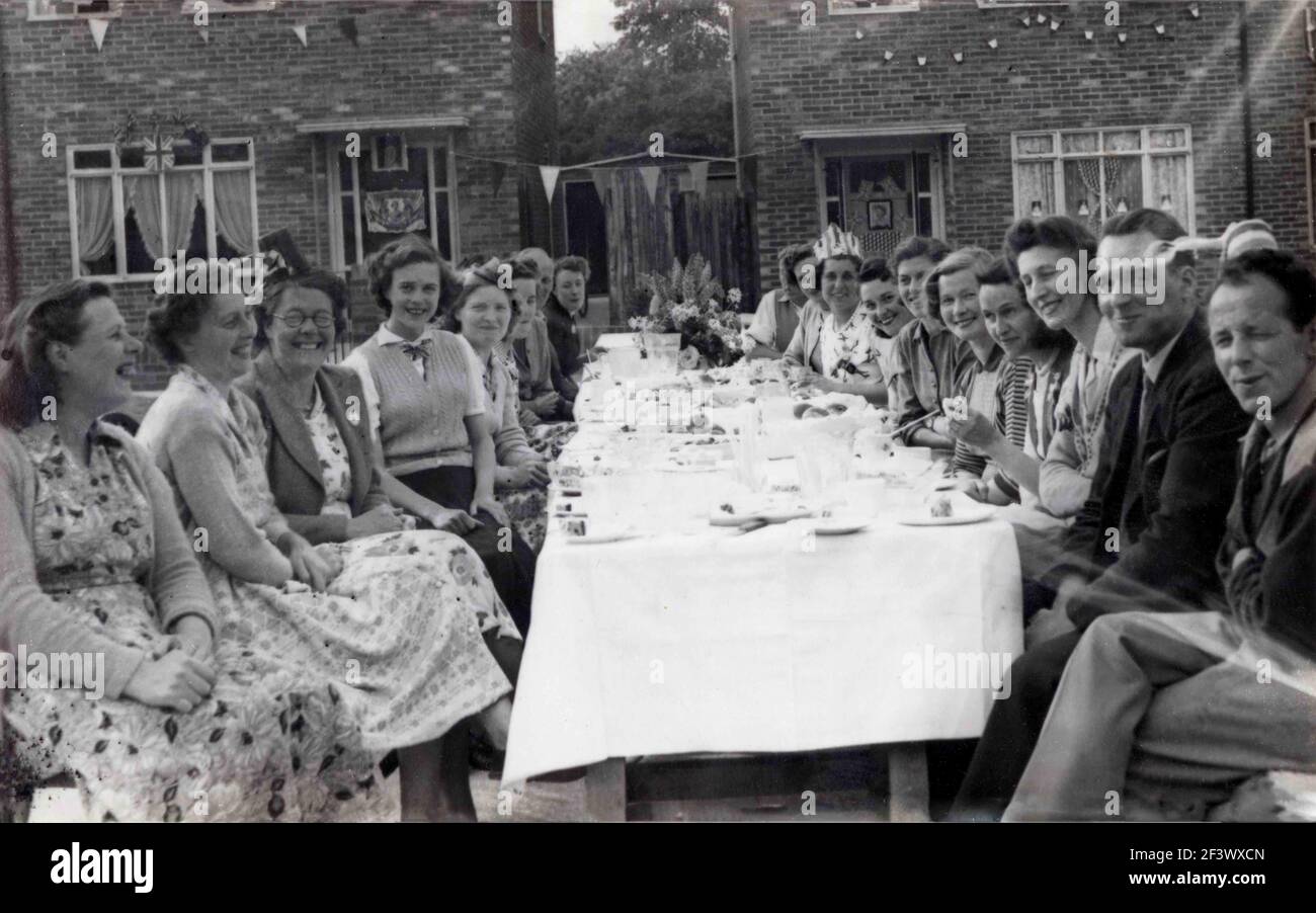 1953, historique, sur un domaine de logement, un groupe de Britanniques hivrant un thé sur de longues tables à l'extérieur, pour célébrer le couronnement de la reine Elizabeth II au trône britannique, qui a eu lieu le 2nd juin 1953 à l'abbaye de Westminster. Banque D'Images
