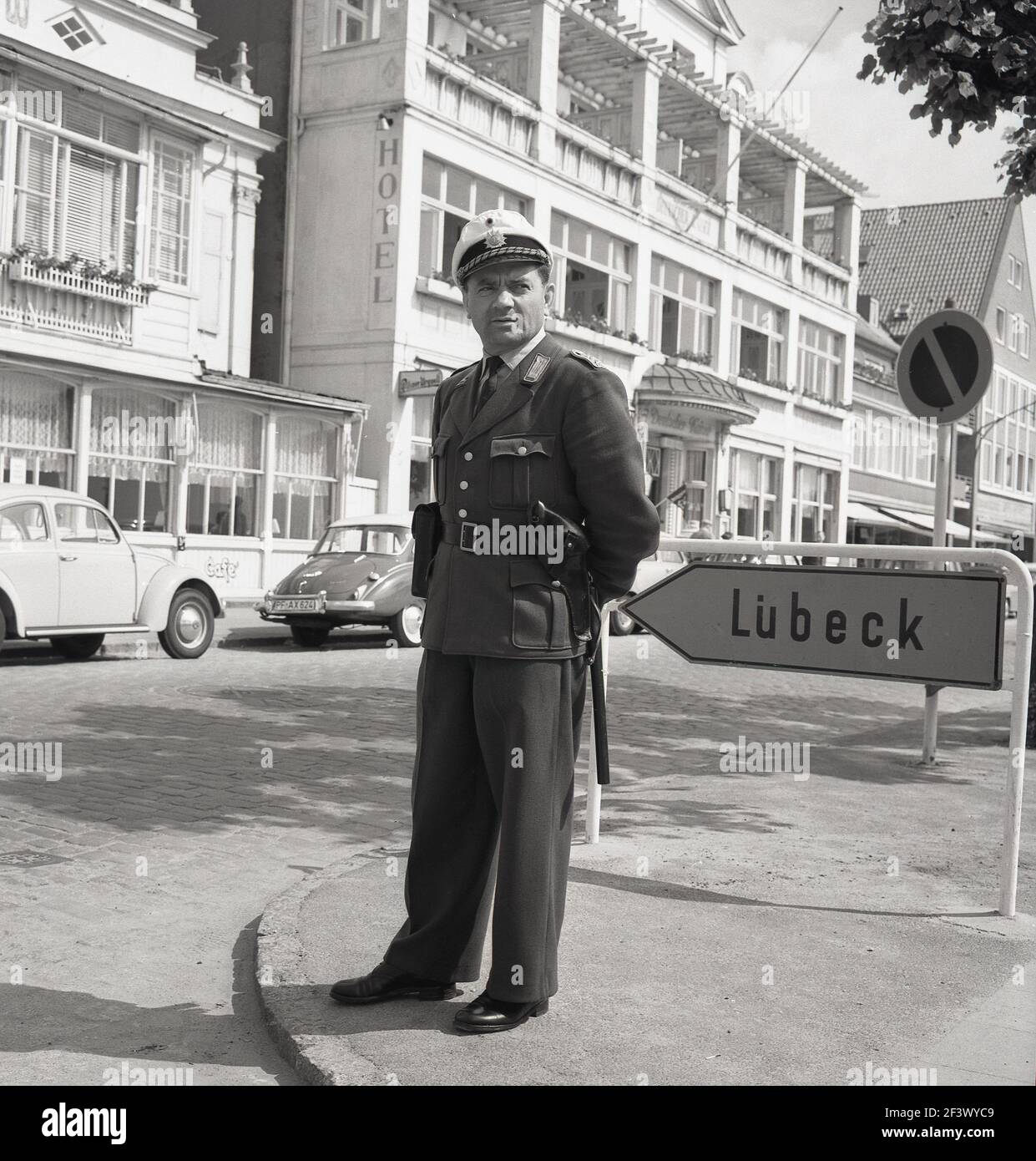 1960s, photo historique par J Allan Cash d'un policier allemand en uniforme, avec chapeau et matraque, debout au coin d'une rue près de Lubeck, la deuxième plus grande ville de l'État du Schleswig-Holstein, Allemagne. Banque D'Images