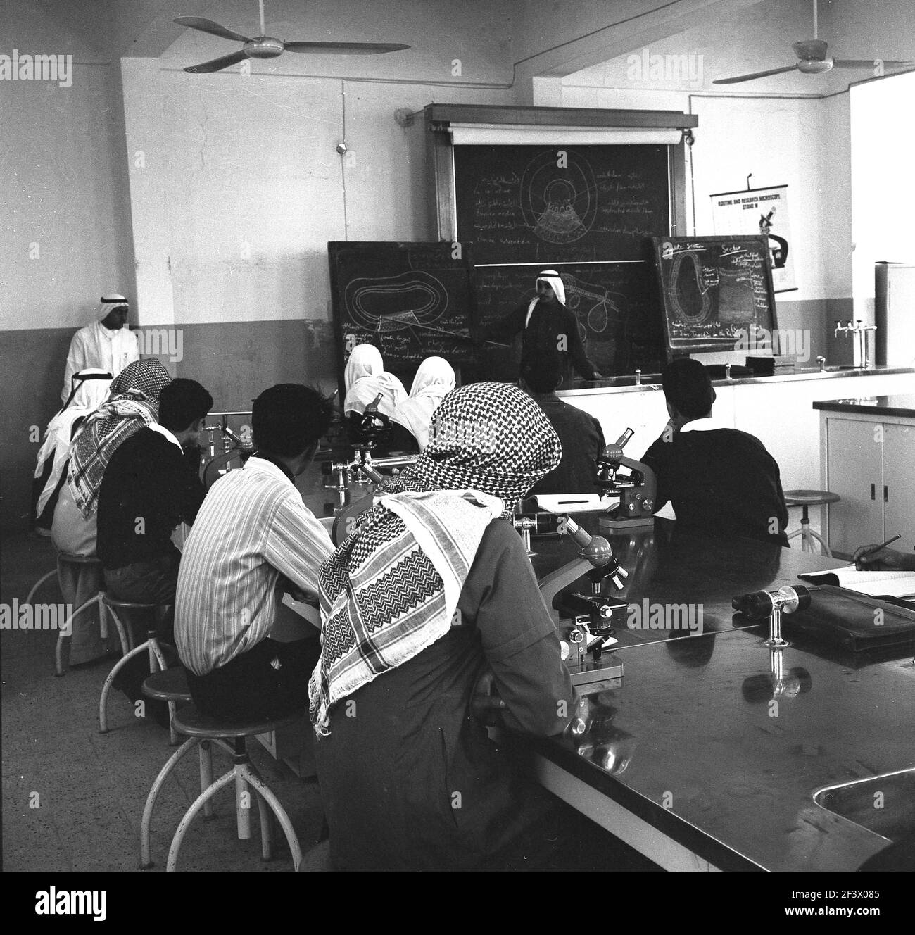 1960s, étudiants arabes historiques dans une salle de classe, avec un professeur au tableau de blackboard, Djeddah, Arabie Saoudite. Banque D'Images