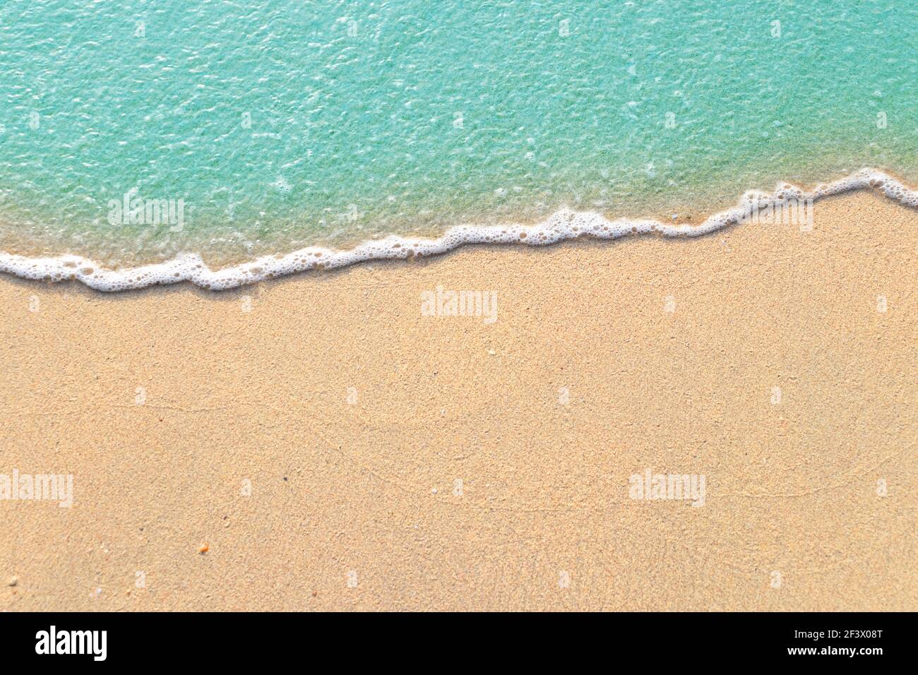 Vagues douces avec mousse de bleu océan sur la plage de sable Banque D'Images