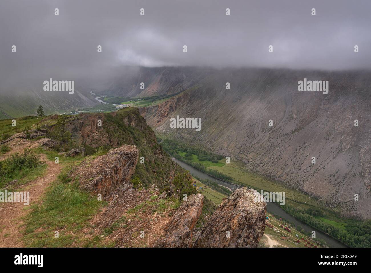 Vue panoramique sur les montagnes, la vallée entre les montagnes, la forêt, la rivière sinueuse et le brouillard sur fond de ciel couvert et de nuages en été. Banque D'Images
