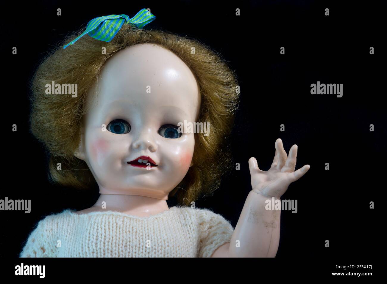 Vieille poupée antique en plastique dur avec des cheveux blonds et des yeux  de regard et en agitant un bras contre un fond noir Photo Stock - Alamy