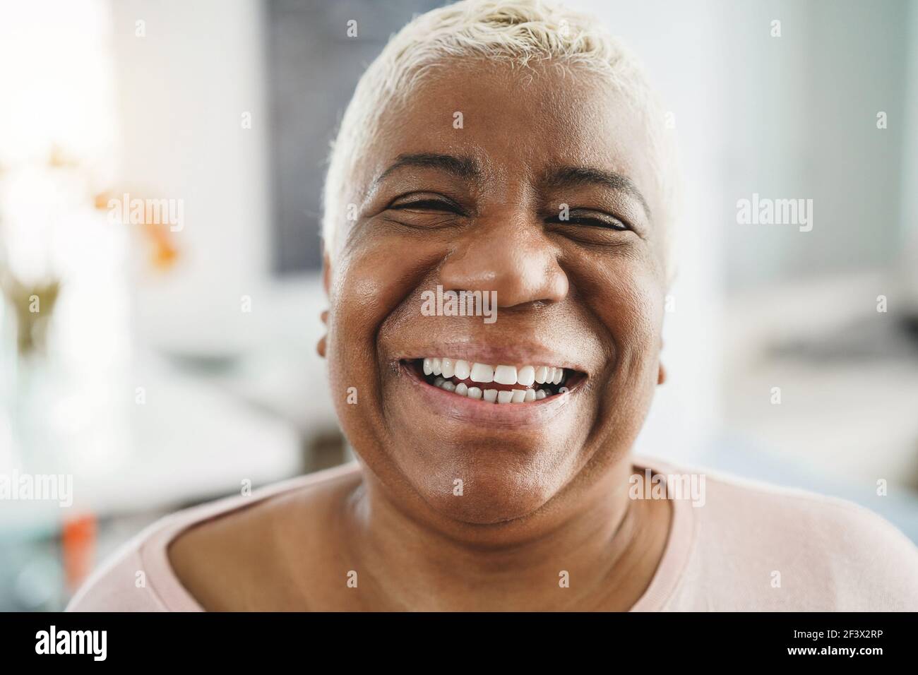 Portrait d'une femme africaine âgée heureuse regardant l'appareil photo à l'intérieur À la maison - concentrez-vous sur le visage Banque D'Images