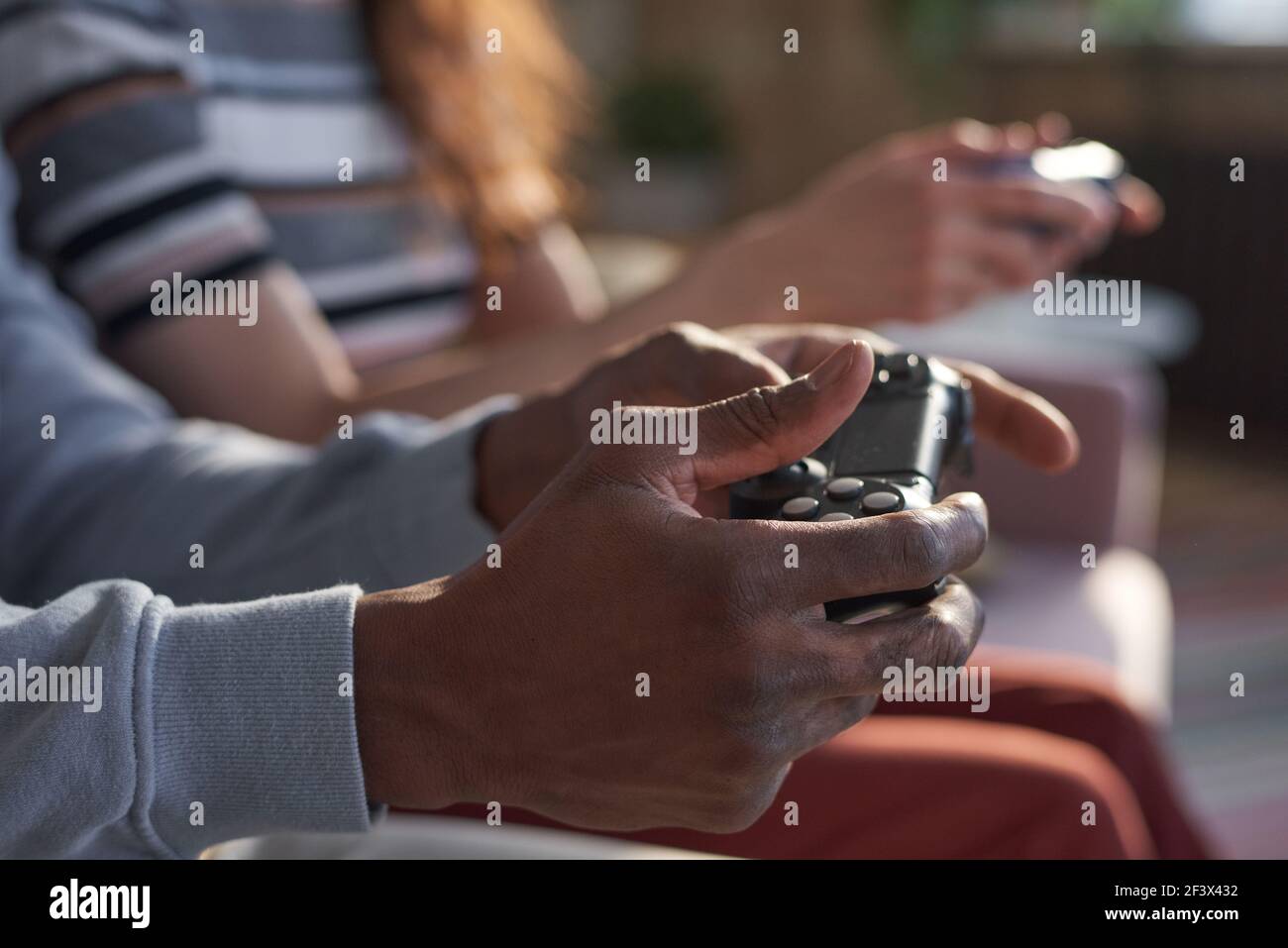 Gros plan d'amis utilisant des manettes de jeu pour jouer ensemble à des jeux vidéo à la maison Banque D'Images