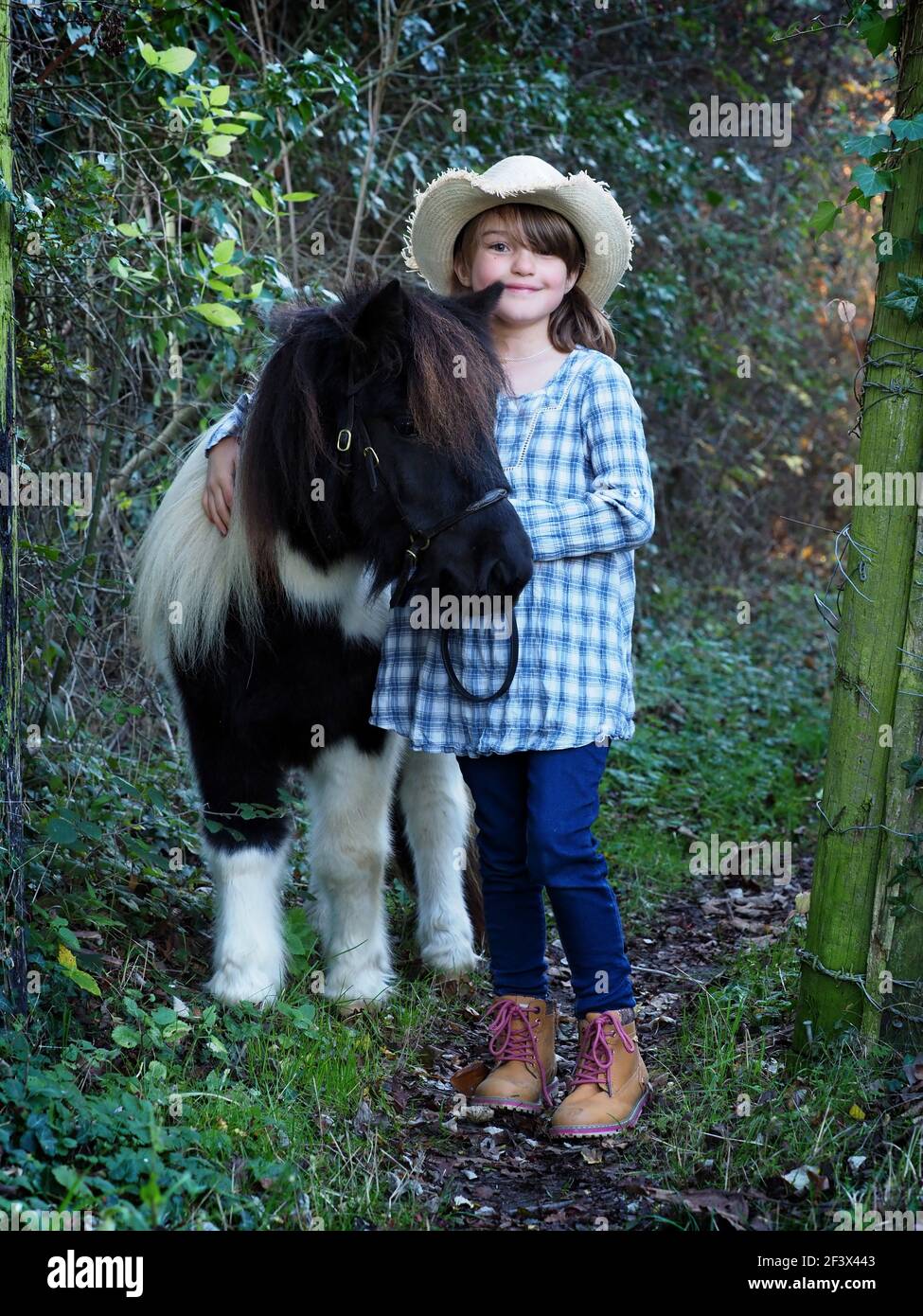 Une fille dehors avec son poney noir et blanc Banque D'Images