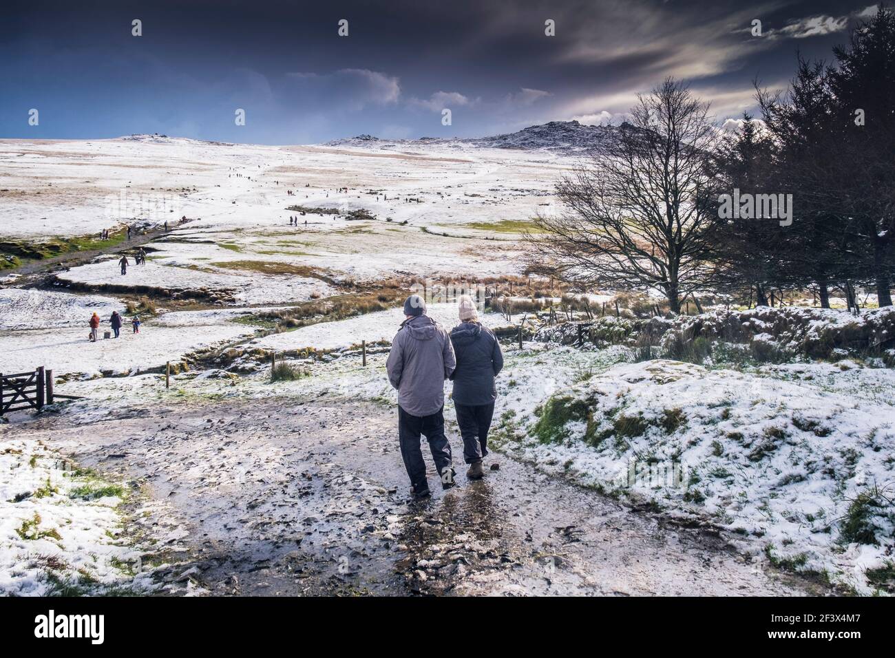Les gens qui apprécient la marche dans la neige sur la sauvage sauvage Rough Tor sur Bodmin Moor dans les Cornouailles. Banque D'Images
