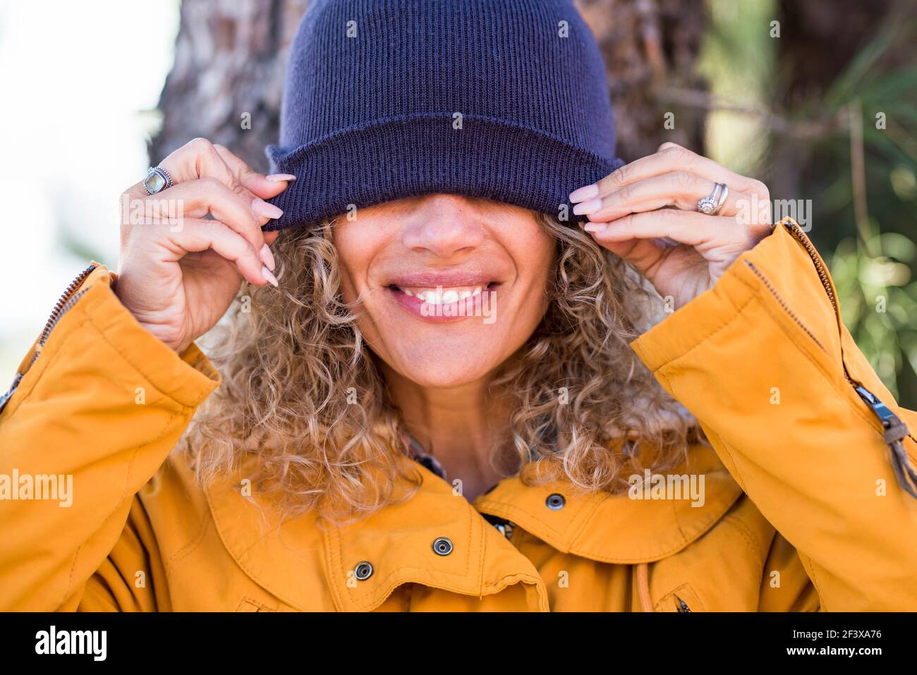 Joyeux adulte beau portrait de femme couvrant ses yeux avec l'hiver tasse - les gens heureux profiter des activités de loisirs en plein air - joli sourire et dents concrènent Banque D'Images