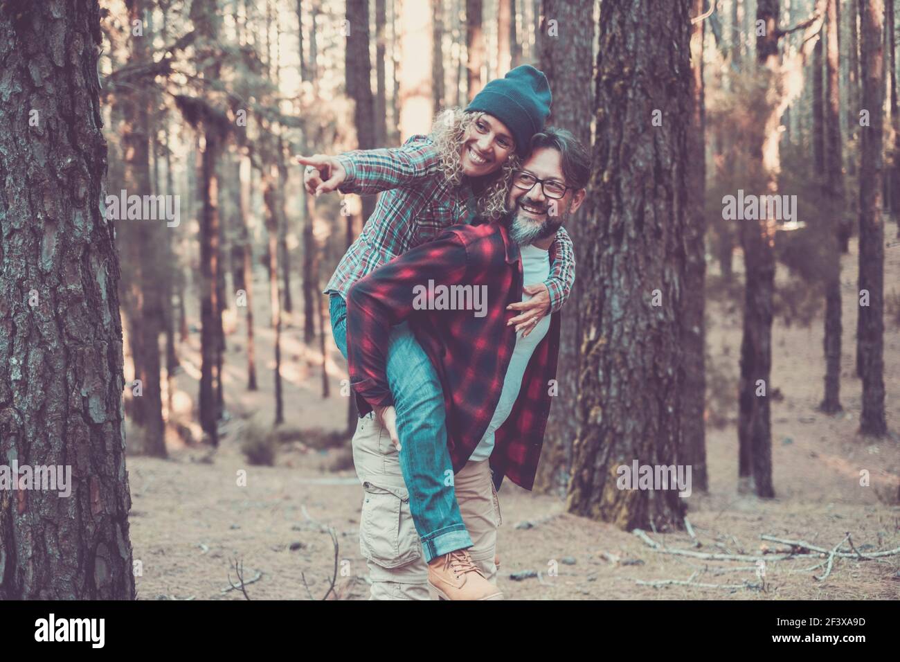 Joyeux et amusant couple caucasien ayant le piggyback tout en marchant sur le sentier dans les bois. Concept d'aventure dans la nature - jeune homme et femme adulte enjo Banque D'Images