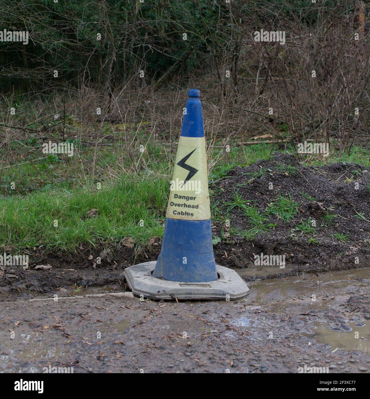 Cône de signalisation bleu et jaune, avertissement de danger câbles aériens Banque D'Images