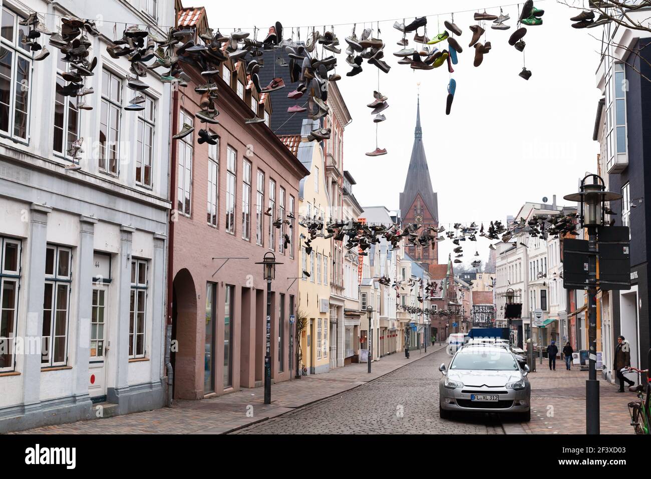 Flensburg, Allemagne - 10 février 2017 : beaucoup de chaussures sportives pendent sur des fils, vue sur la rue de Flensburg. Les gens ordinaires marchent dans la rue Banque D'Images