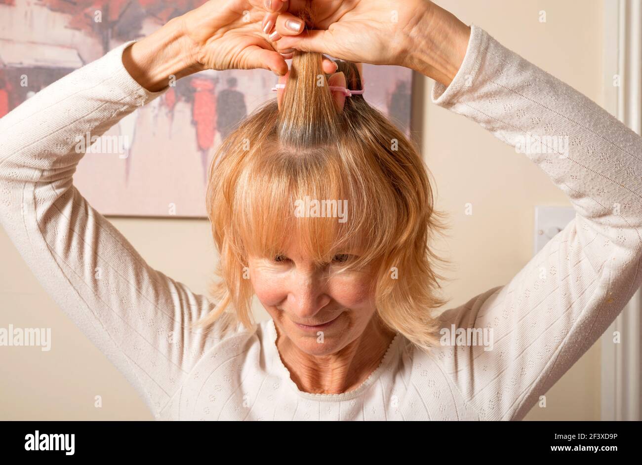 Femme mettant ses cheveux dans des friser Banque D'Images