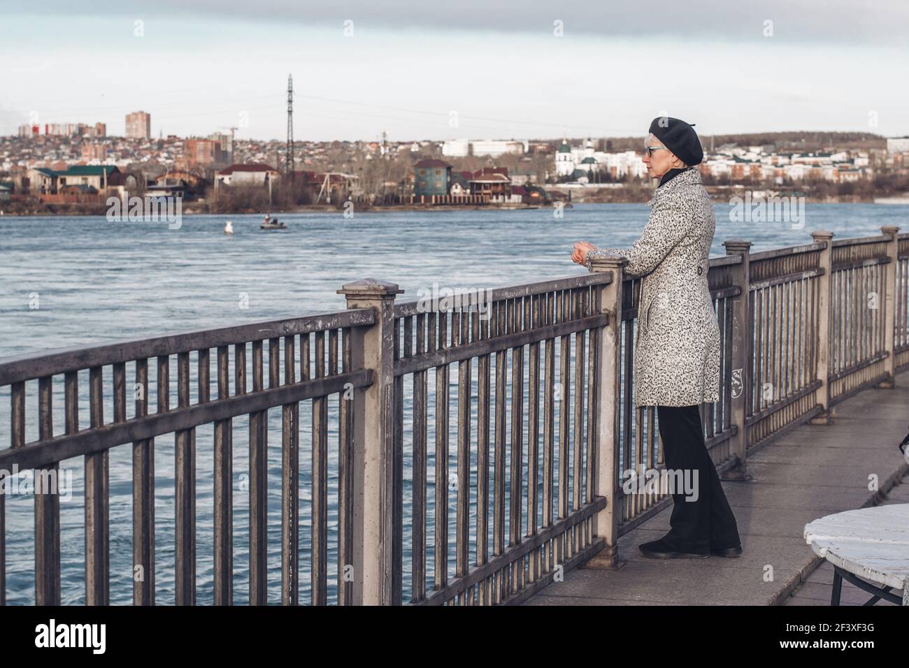 Une femme d'âge moyen élégante se tient sur le remblai de la rivière et regarde dans la distance.solitude, réflexion, détente dans un environnement urbain Banque D'Images