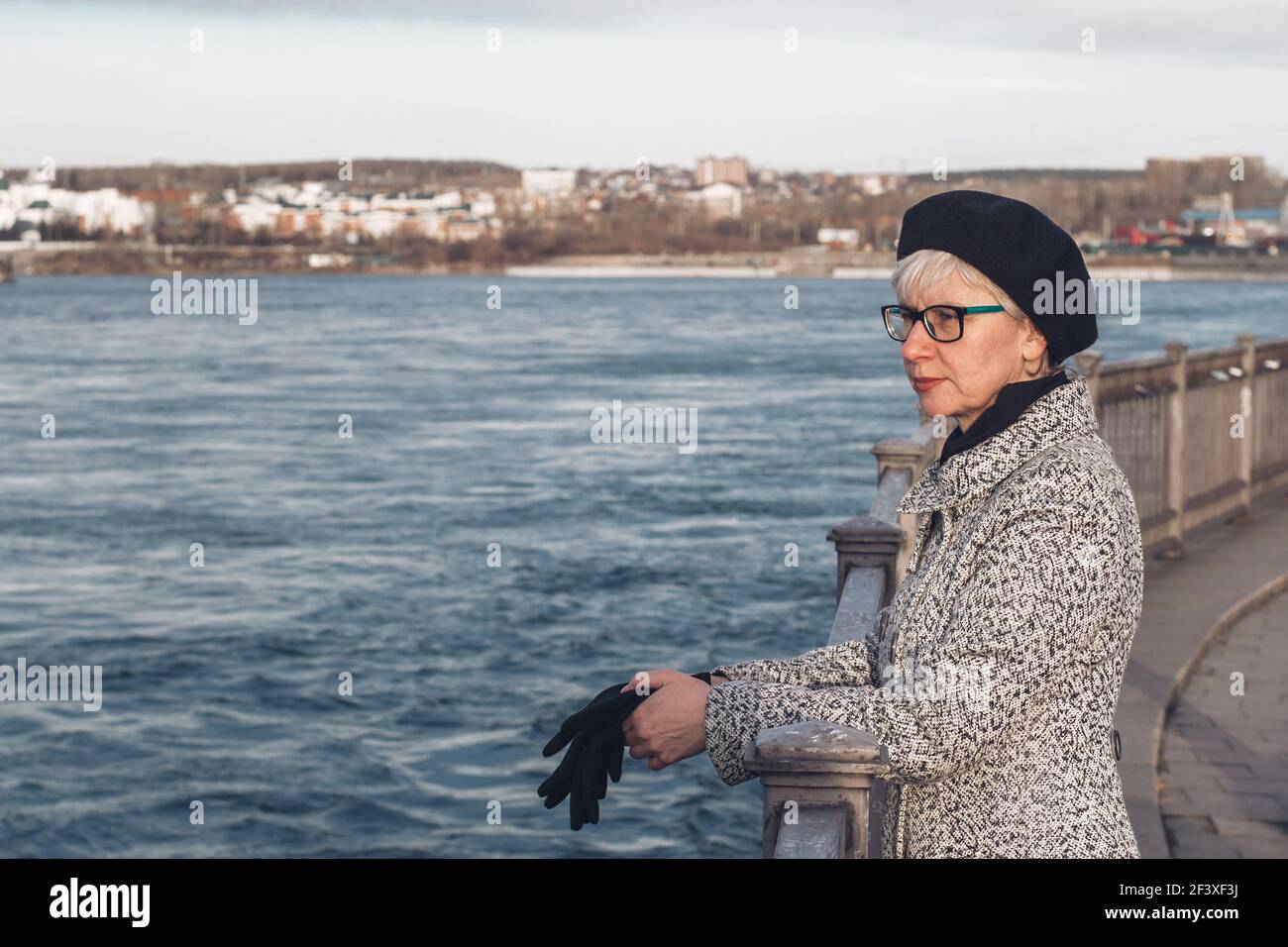 Portrait d'une femme d'âge moyen élégante en lunettes sur le talus de la rivière. Un regard pensif dans la distance.solitude, réflexion, relaxation Banque D'Images