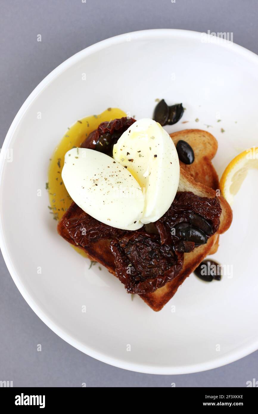 Petit-déjeuner maison composé de toasts avec tomates séchées et œufs pochés sur le dessus. Concept de la cuisine à la maison. Banque D'Images