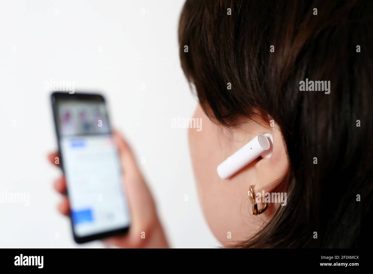 Femme avec casque sans fil dans les oreilles. Casque, écouter de la musique et regarder de la vidéo Banque D'Images