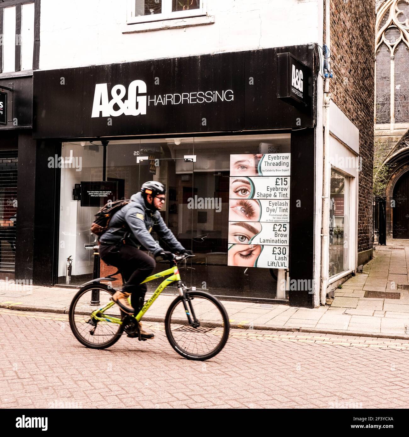 Londres UK, mars 18 2021, Man Riding A Bicylcle passant UN coiffeurs fermé Shop Covid-19 coronavirus Lockdown Banque D'Images
