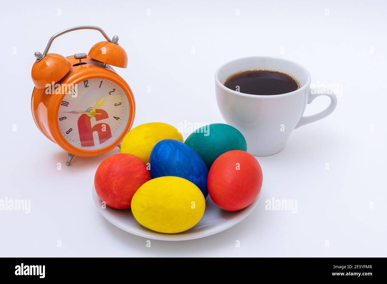 Concept petit déjeuner de Pâques. Œufs de Pâques peints à la main, mug avec café ou chocolat chaud, réveil. Concept joyeuses Pâques. Il est temps de célébrer Pâques Banque D'Images