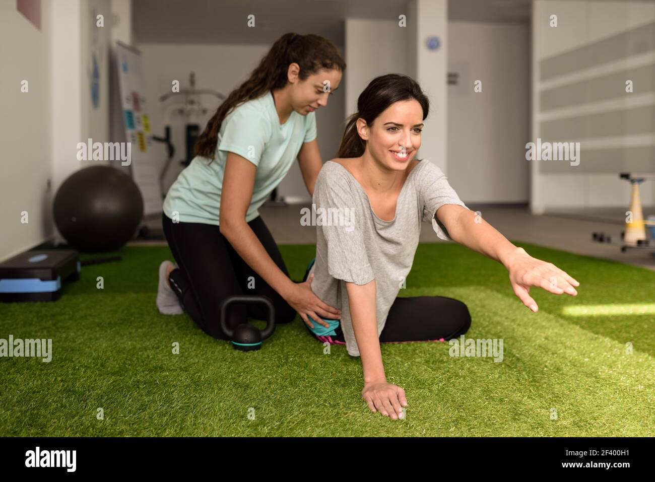 Thérapeute physique aider young caucasian woman avec l'exercice au cours de la réadaptation dans le gymnase de l'hôpital. La formation de physiothérapeute femelle un patient dans un centre de physiothérapie. Banque D'Images