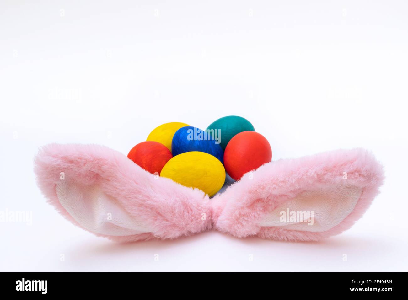Concept joyeuses Pâques. Œufs de Pâques peints à la main et oreilles de lapin roses sur fond blanc. Carte de Pâques minimaliste. Banque D'Images