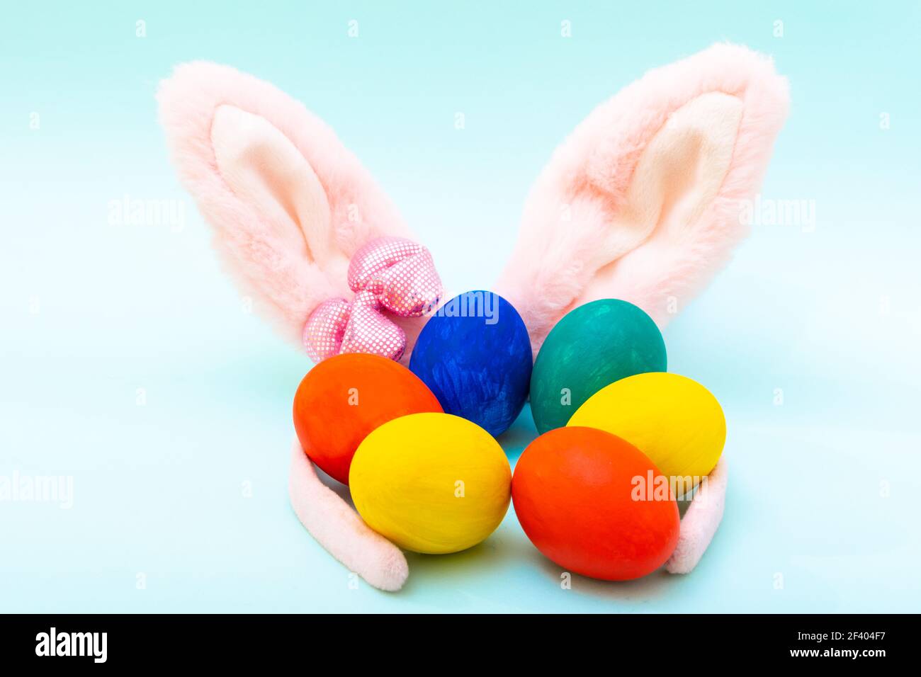 Concept joyeuses Pâques. Œufs de Pâques peints à la main et oreilles de lapin roses sur fond bleu, gros plan. Carte de Pâques minimaliste Banque D'Images