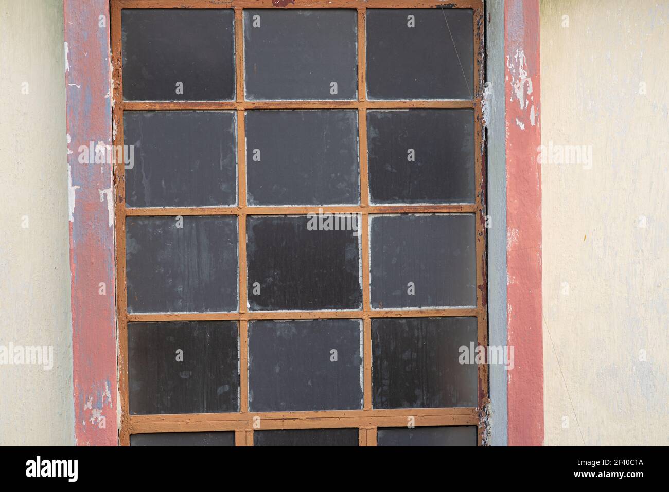Une belle photo d'une vieille fenêtre avec des grilles, des taches et des fissures sur un mur de ciment Banque D'Images