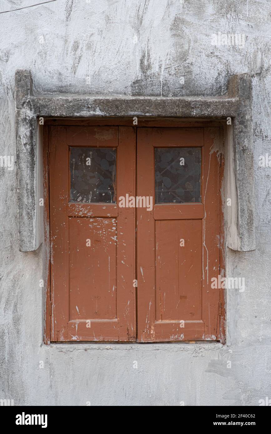 Un cliché vertical d'une ancienne fenêtre en bois avec des taches et des fissures sur un mur de ciment Banque D'Images