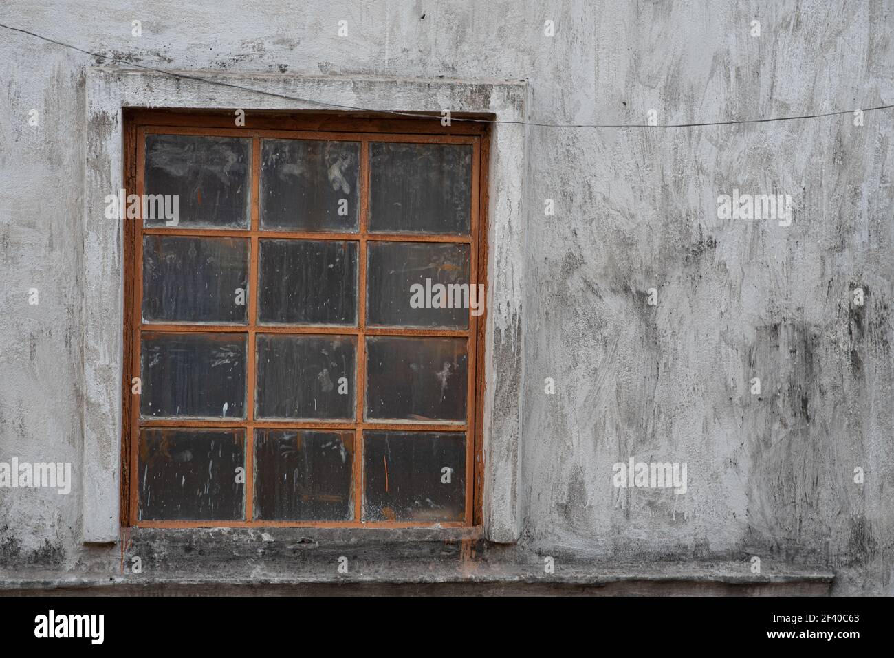 Une belle photo d'une vieille fenêtre avec des grilles, des taches et des fissures sur un mur de ciment Banque D'Images