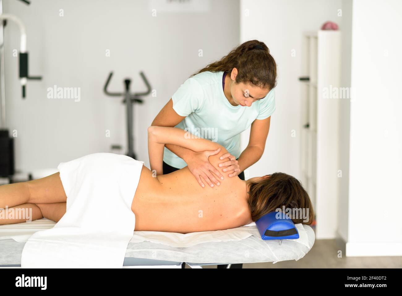 Les professionnels d'un physiothérapeute massage épaule donnant à brunette woman à l'hôpital. Contrôle médical à l'épaule dans un centre de kinésithérapie. Banque D'Images