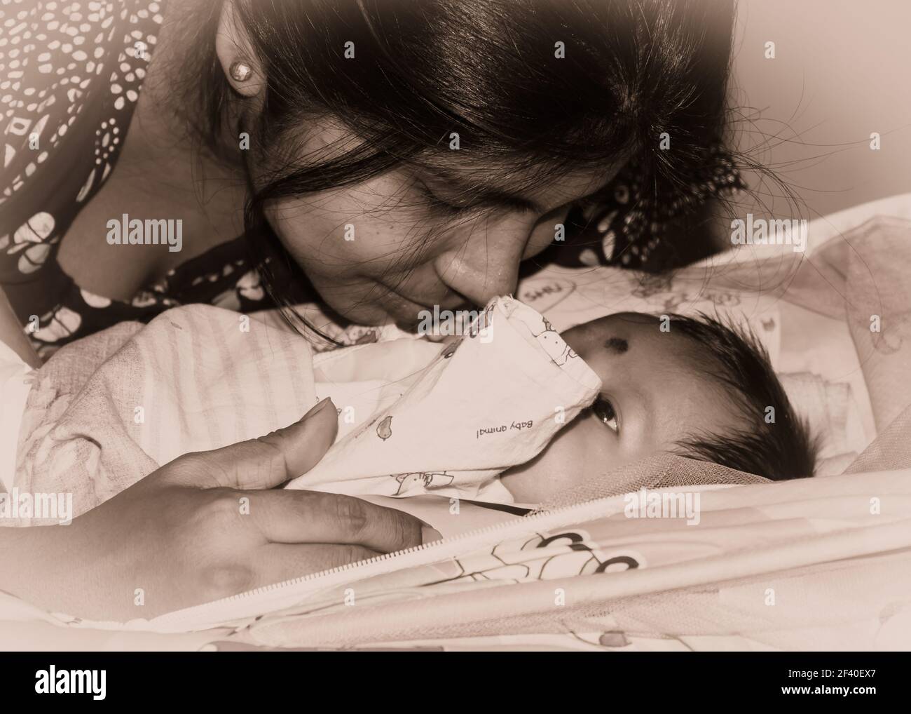 Adorable nouveau-né bébé garçon embrassé par la mère dans son tour de mère allongé sur le lit. Gros plan. Bébé Sweet Little d'un mois. Ethnie indienne. Vue avant Banque D'Images