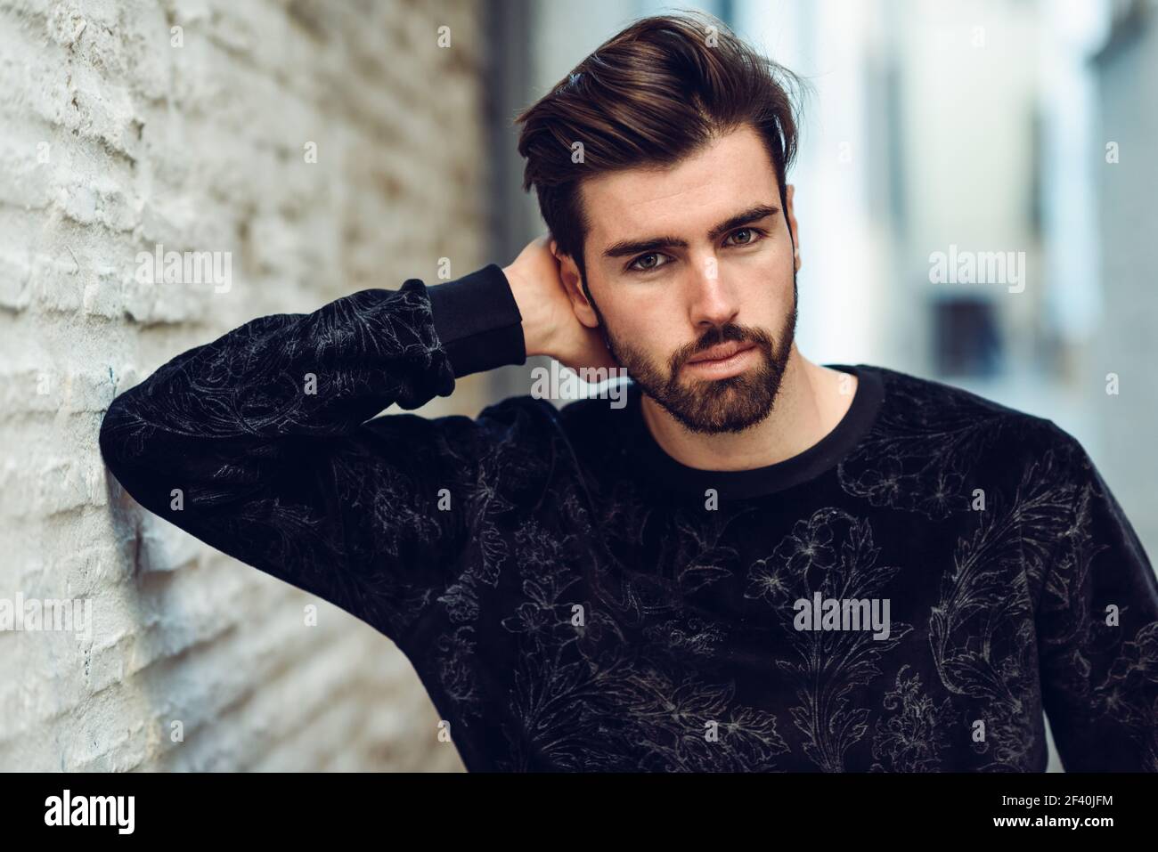 Jeune homme barbu, modèle de mode, regardant l'appareil photo en milieu urbain portant des vêtements décontractés. Gars avec la barbe et la coiffure moderne dans la rue. Jeune homme barbu, modèle de mode, en milieu urbain portant des vêtements décontractés. Banque D'Images