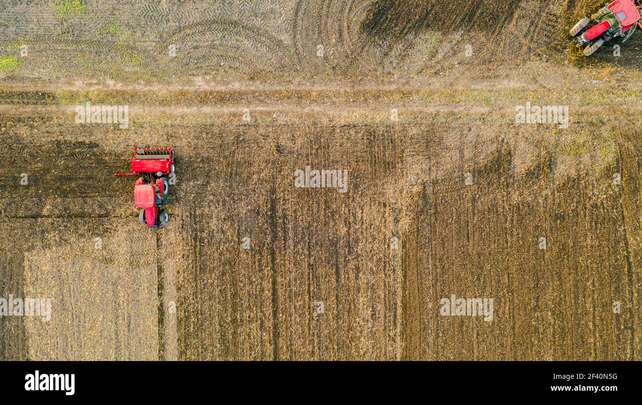 Vue aérienne de dessus de trois tracteurs, l'un traînant une herse à disque et l'autre un cultivateur de semis, le troisième tirant la machine de semoir sur le fie arable Banque D'Images