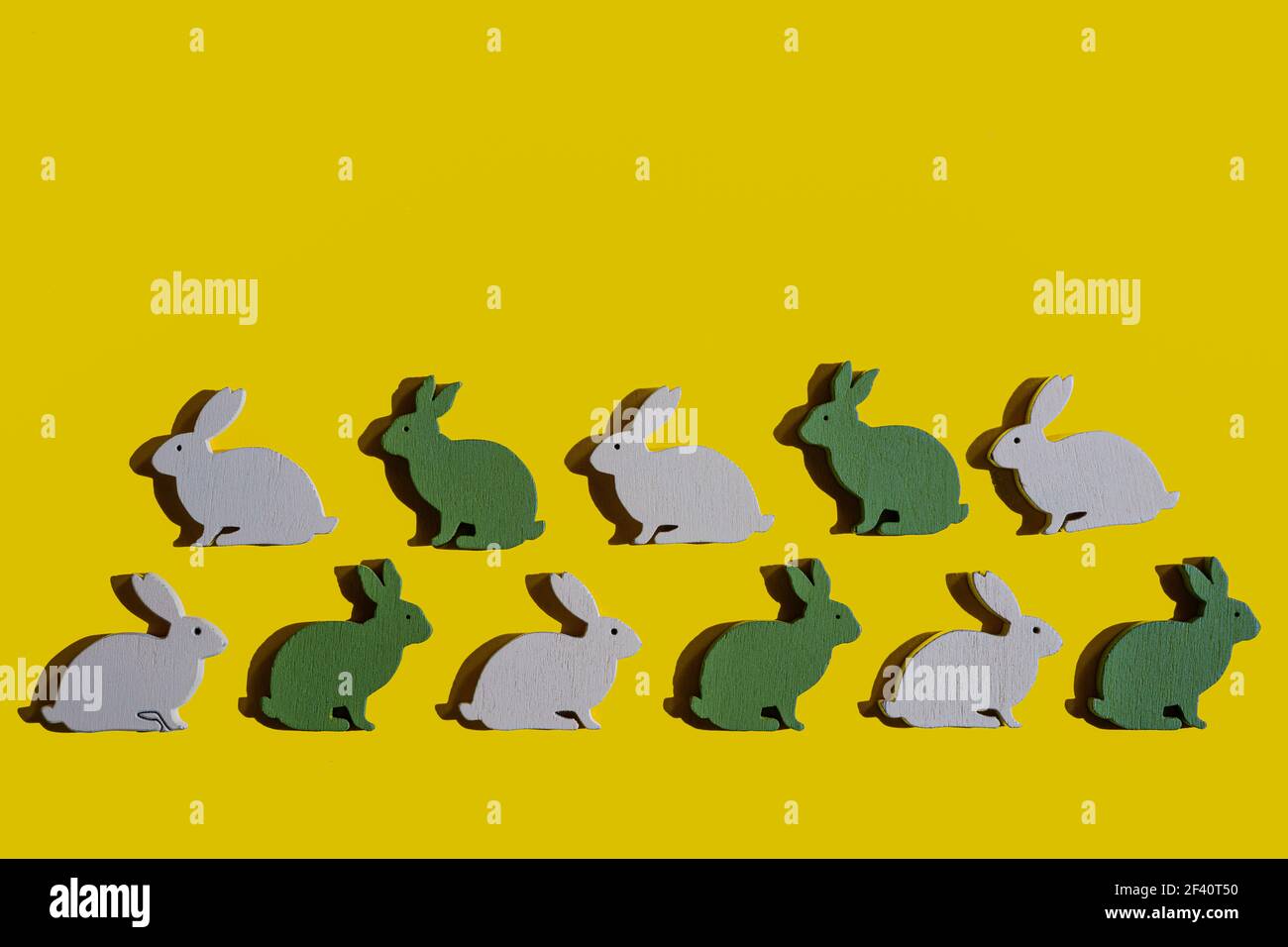 Quelques lapins en bois de Pâques sur une surface jaune Banque D'Images