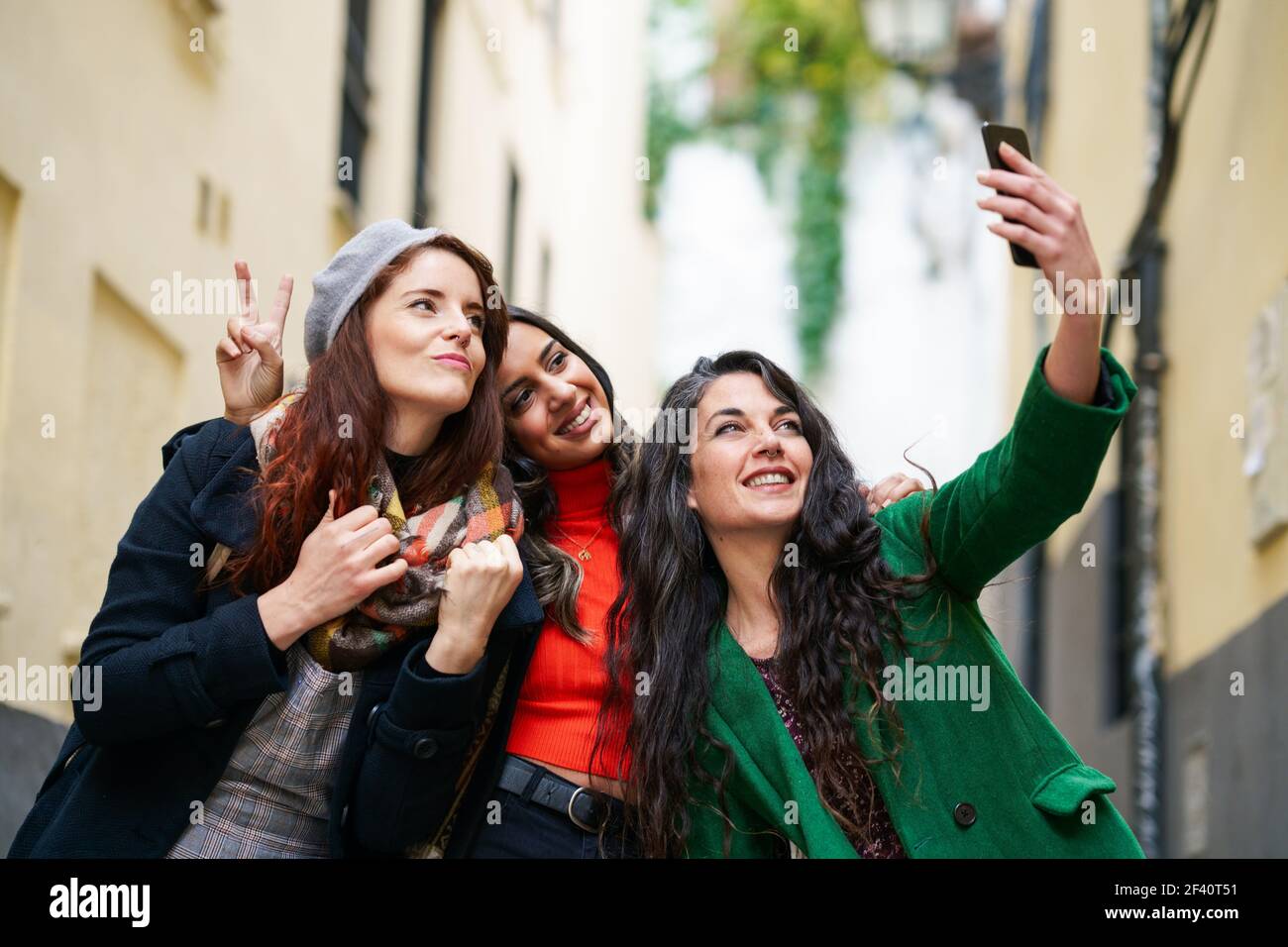 Groupe multiethnique de trois femmes heureuses prenant une photo de selfie avec un smartphone en milieu urbain. Groupe de trois femmes heureuses marchant ensemble à l'extérieur Banque D'Images