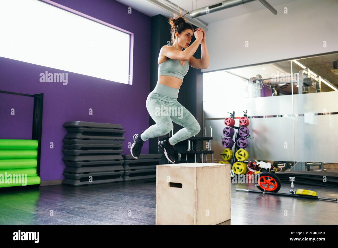 Une femme de fitness sautant sur une boîte dans le cadre de la routine d'exercice. Une femme caucasienne fait de l'entraînement de saut à la boîte à la salle de gym. Une femme de fitness sautant sur une boîte dans le cadre de la routine d'exercice. Banque D'Images