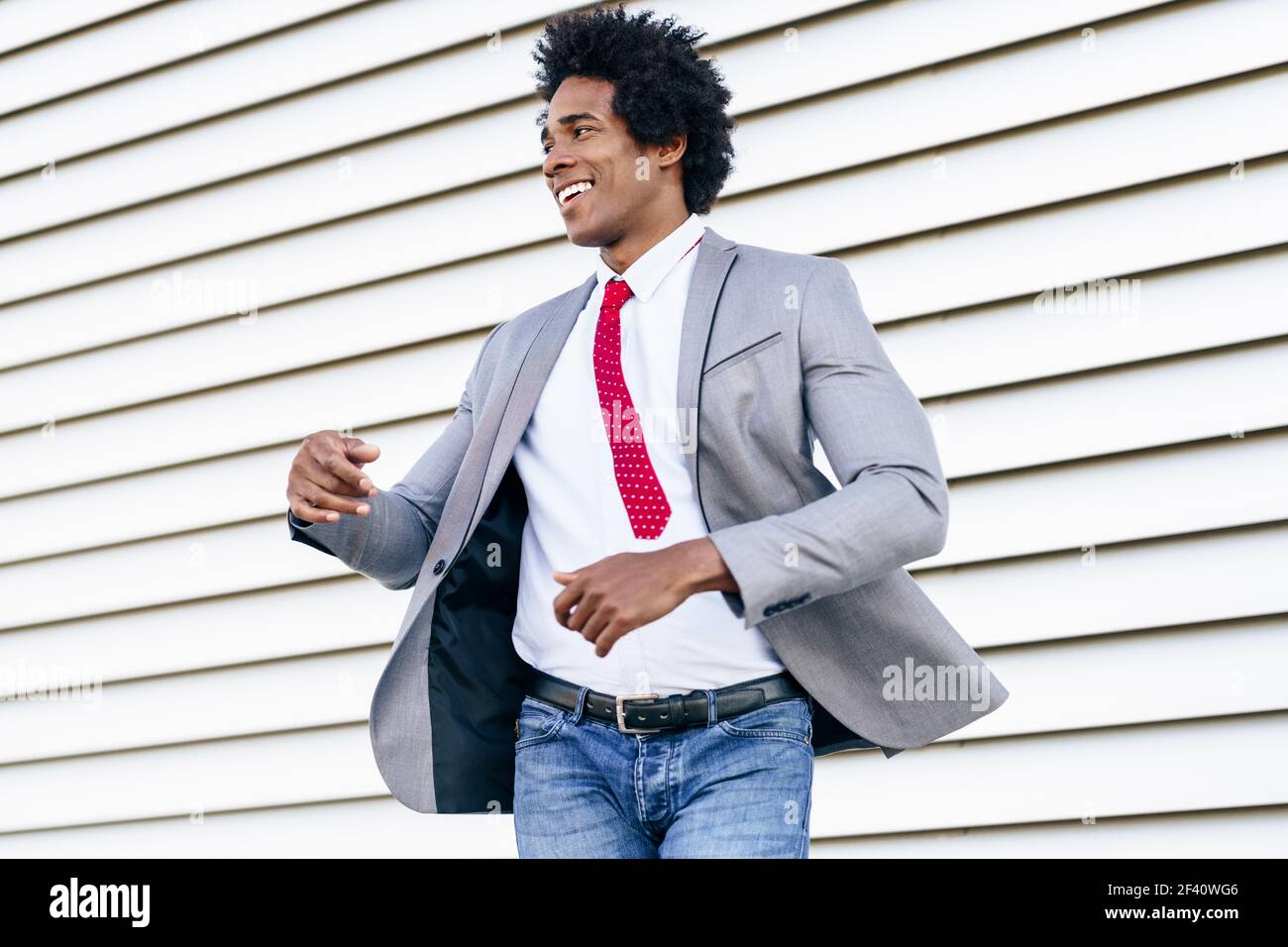 Joyeux homme d'affaires noir vêtu d'un costume dansant à l'extérieur. Homme avec cheveux afro.. Joyeux homme d'affaires noir vêtu d'un costume dansant à l'extérieur. Banque D'Images