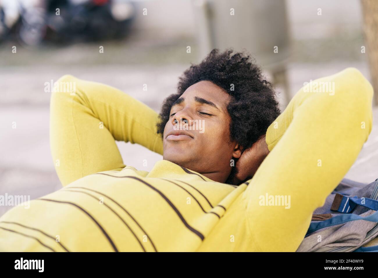 Touriste noir cubain avec des cheveux afro couchés sur le sol, sur son sac à dos, se reposant de son voyage à Grenade, Andalousie, Espagne. Touriste noir avec des cheveux afro couchés au sol à l'extérieur. Banque D'Images