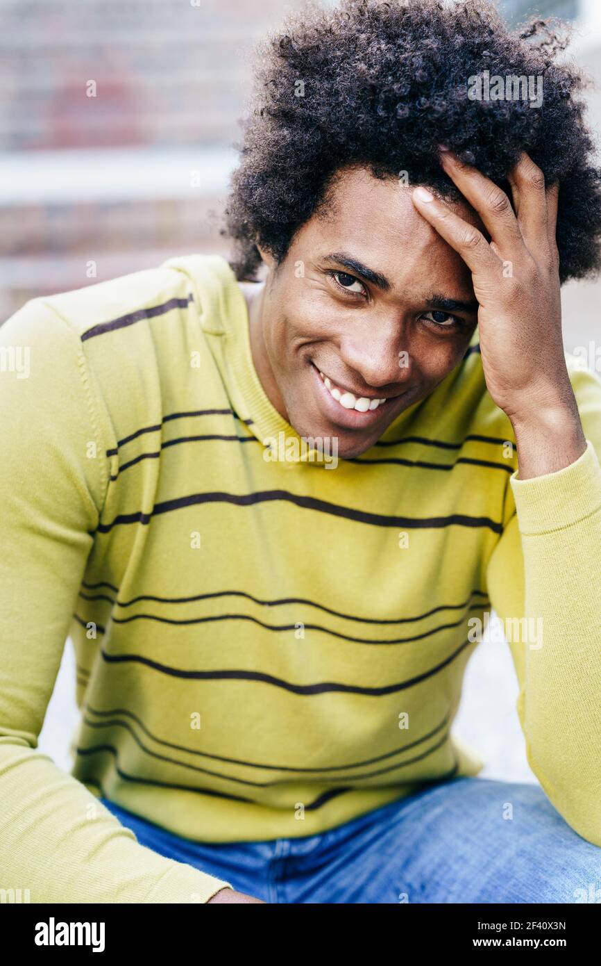 Touriste noir cubain avec des cheveux afro assis sur le sol souriant à l'appareil photo. Touriste noir cubain avec cheveux afro assis sur le sol Banque D'Images