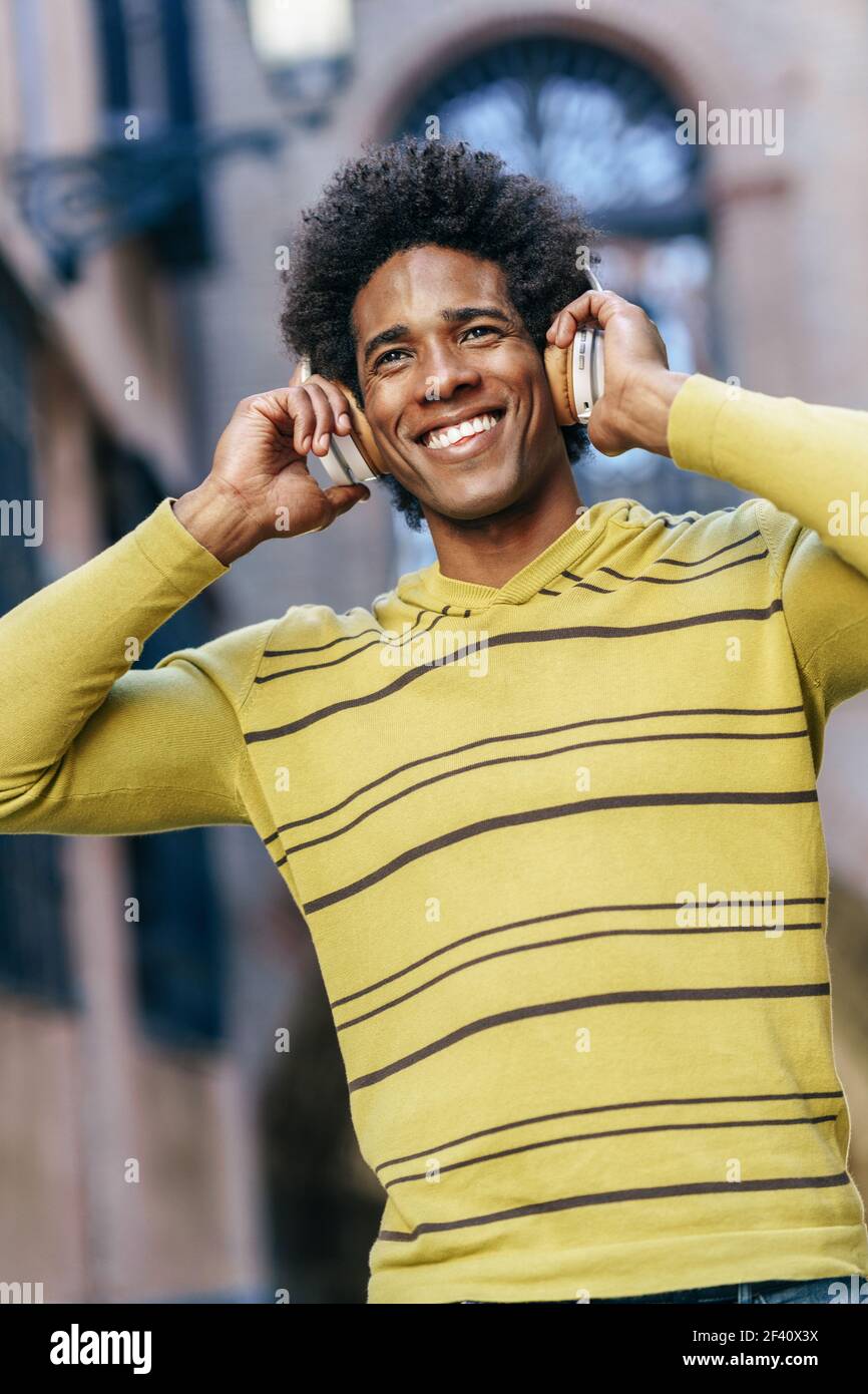 Homme noir avec cheveux afro écouter de la musique avec des écouteurs sans fil visite à Grenade, Andalousie, Espagne. Black man écoutant de la musique avec des écouteurs sans fil visite de Grenade Banque D'Images
