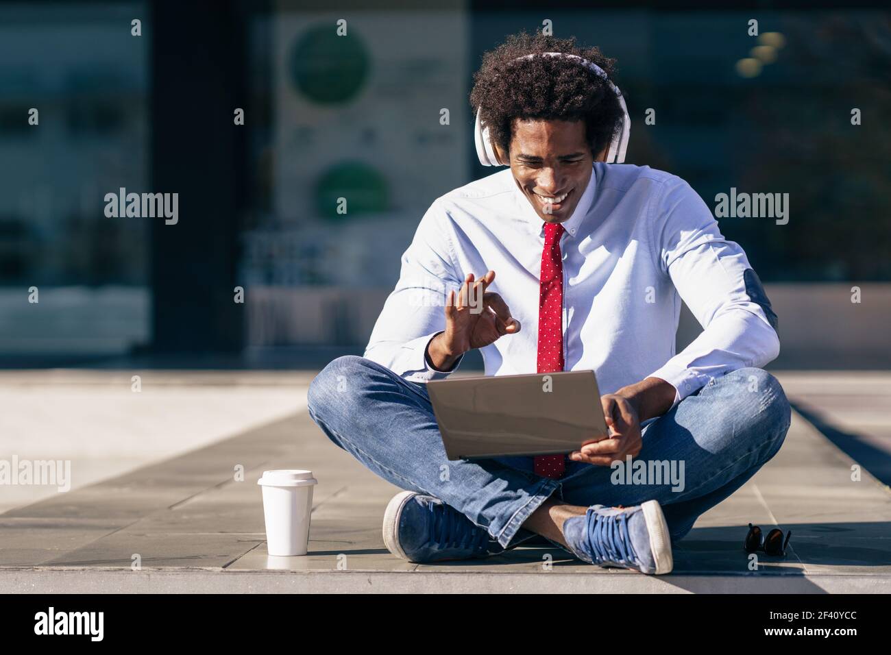 Homme d'affaires noir ayant une vidéoconférence avec ordinateur portable et casque Homme avec cheveux afro.. Homme d'affaires noir utilisant un ordinateur portable et un casque Banque D'Images